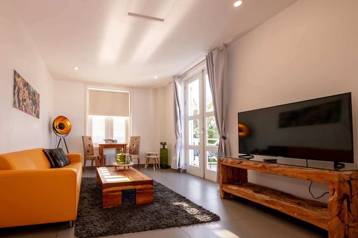 Un salon moderne comprenant un canapé, une table basse, un téléviseur et un coin repas avec des chaises et une table.
