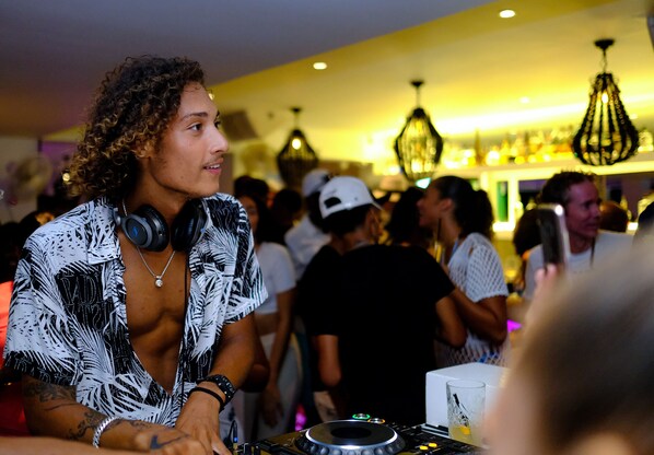 A crowded indoor setting with people and DJ equipment.
