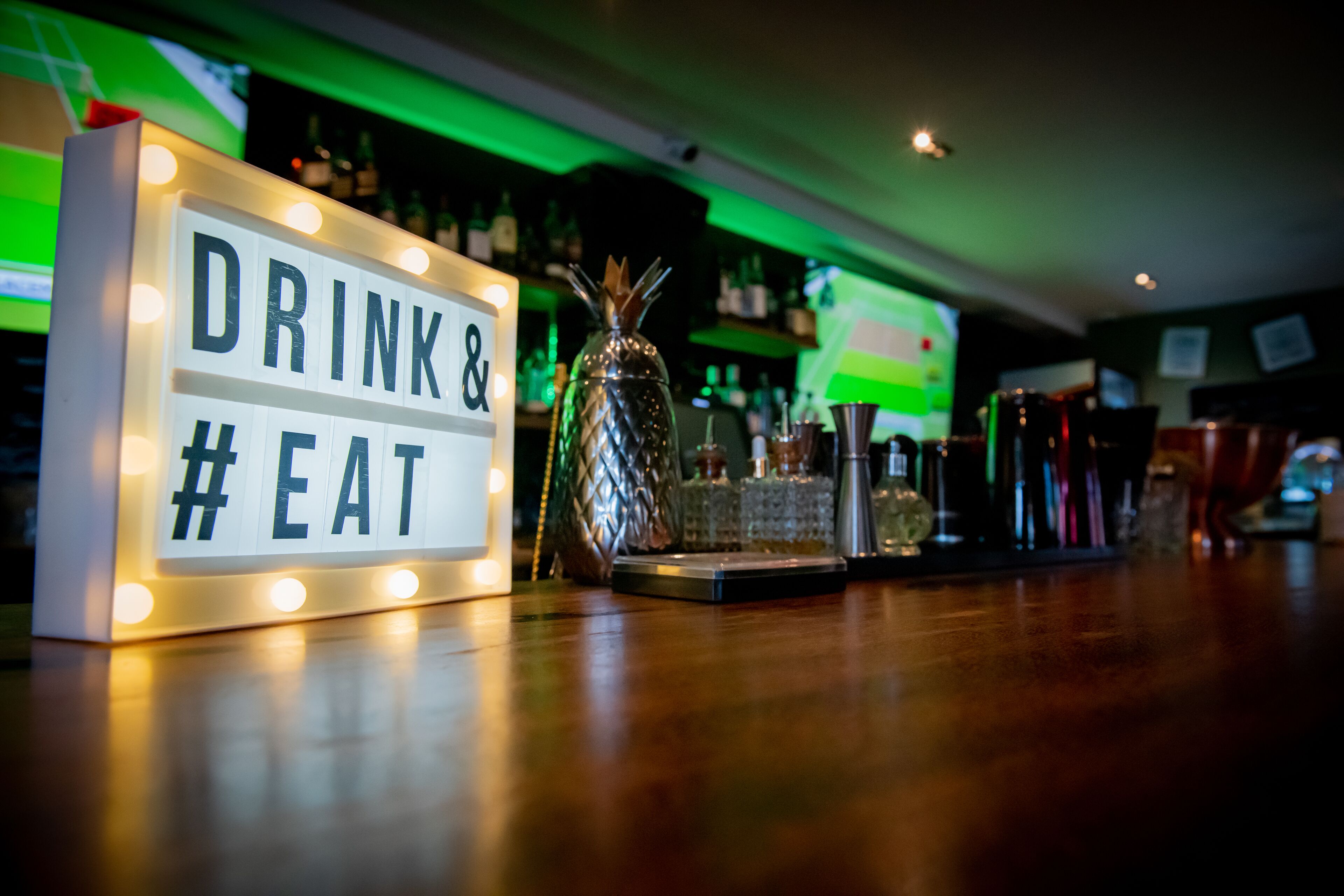 A bar area with a sign that reads "DRINK & EAT".