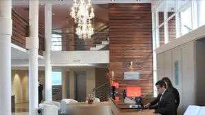 Un vestíbulo de hotel con una recepción, una araña y una escalera.