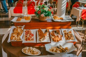 Una mesa de bufé con varios pasteles y un centro de mesa floral.