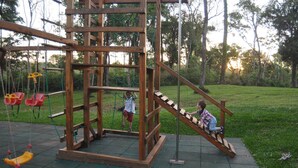 Un parque infantil con una estructura de madera para escalar y columpios.