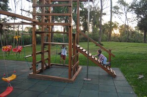Ein Spielplatz mit einer Holz-Kletterkonstruktion und Schaukeln.