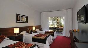 A hotel room with two beds, a TV, a balcony with a table and chairs, and a window with curtains. - Gran Hotel Tourbillon Cataratas (Puerto Iguazú)