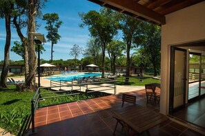 Zona de piscina con patio, mobiliario exterior y vistas al entorno arbolado.