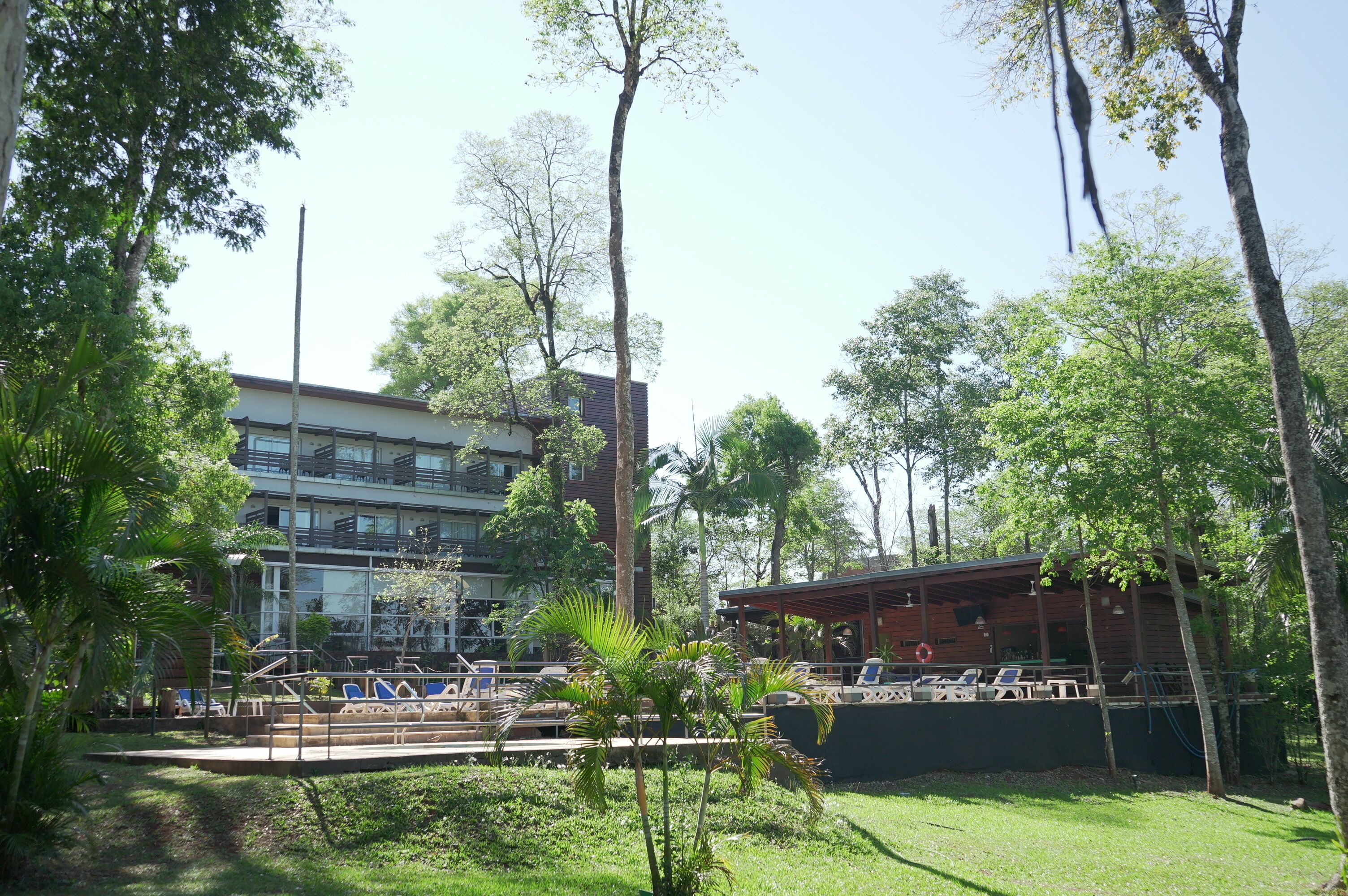 Um hotel com área de piscina, rodeado por árvores e vegetação.