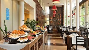 Un bufé con diversos alimentos, una larga barra y un área de comedor con mesas y sillas.