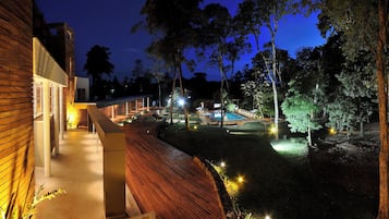 Un espace extérieur moderne doté d’une piscine, d’une terrasse en bois et de chemins bien éclairés.