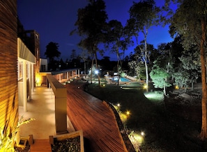A modern outdoor area with a pool, wooden deck, and well-lit pathways.