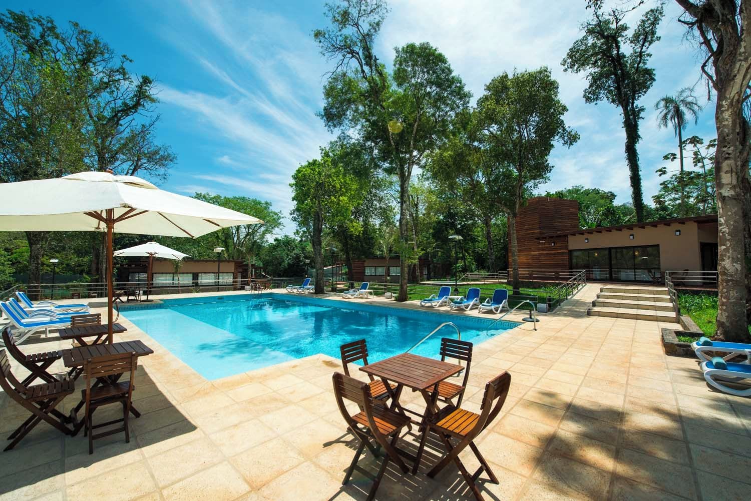 Area piscina con sedie a sdraio, un tavolo e ombrelloni.
