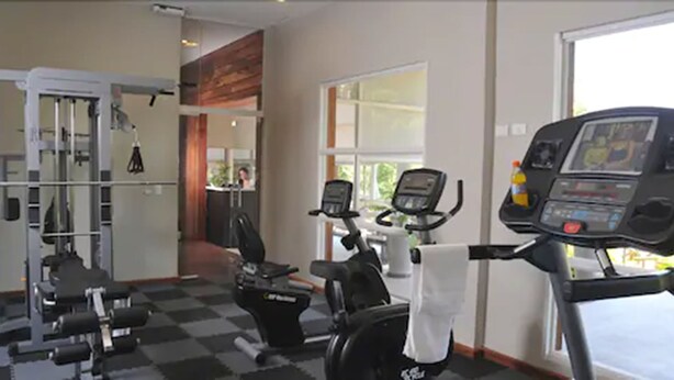 Un gimnasio con máquinas de cardio, equipo de pesas y un amplio ventanal.