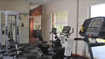 Une salle de sport équipée de machines de cardio, d’appareils de musculation et dotée d’une grande fenêtre.