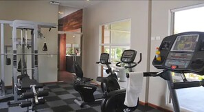 Ein Fitnessraum mit Cardiogeräten, Gewichtstrainern und einem großen Fenster.