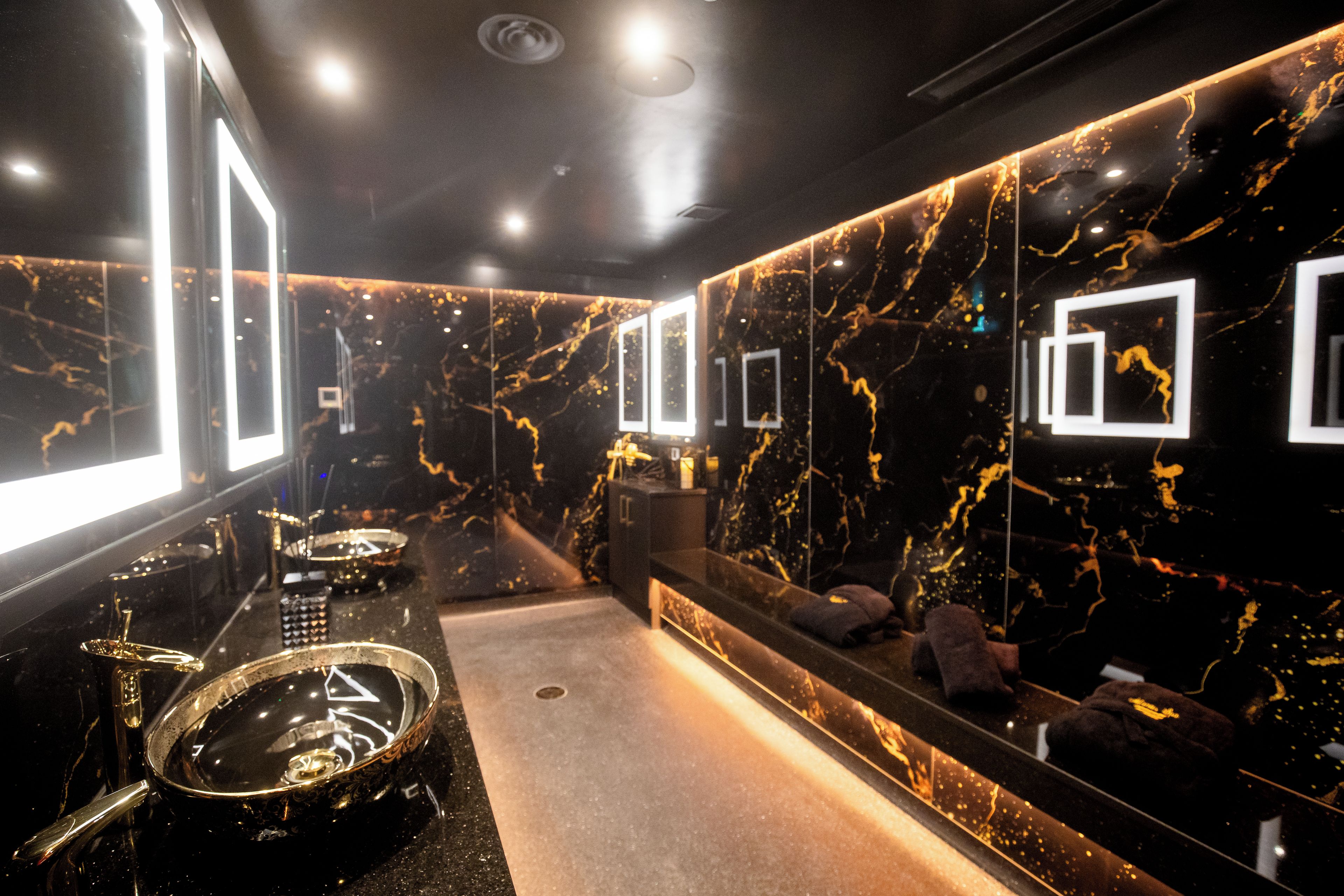 Un baño moderno con pared de mármol, un lavamanos y un espejo.