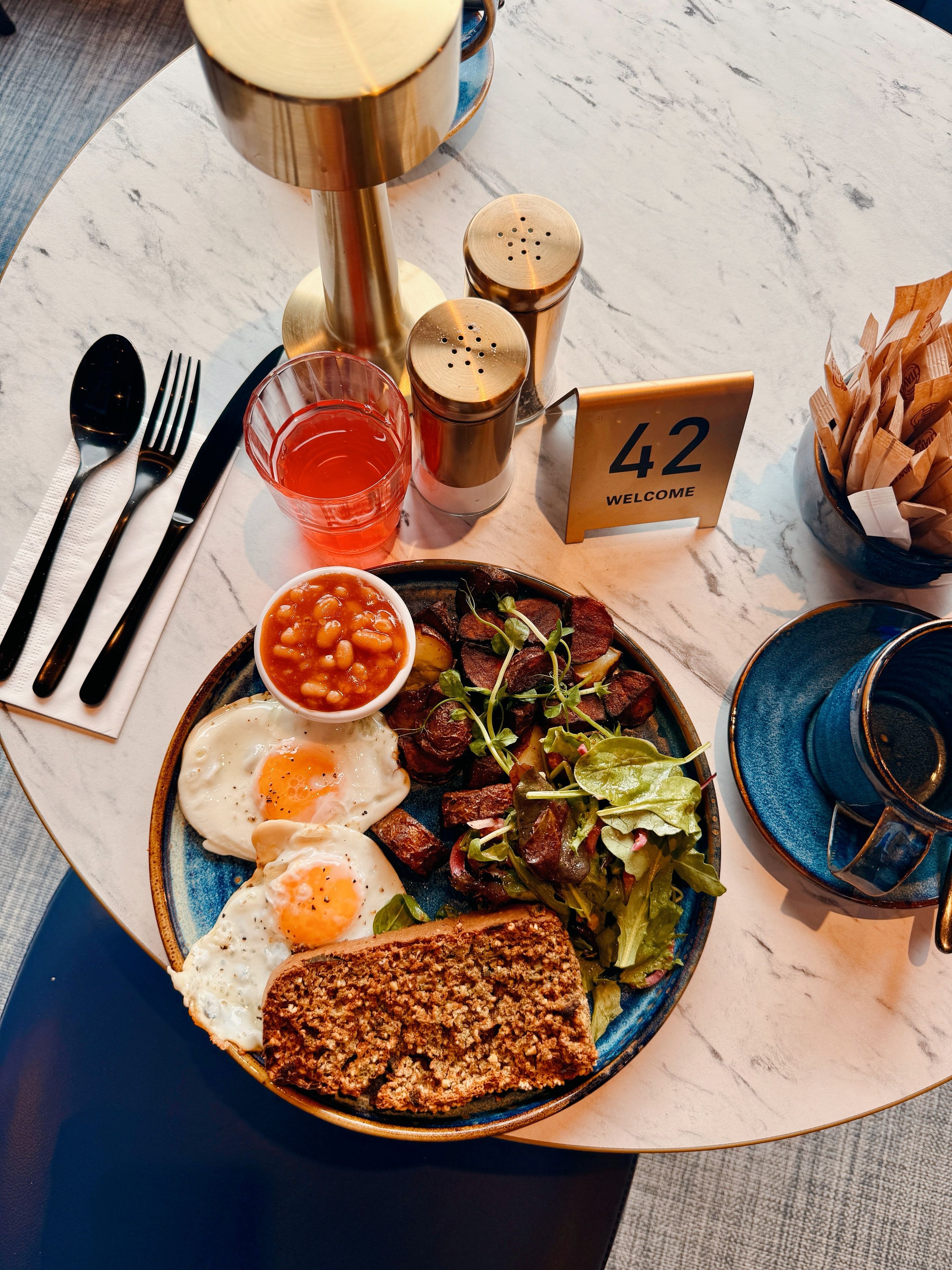 Un plato de desayuno con huevos, frijoles, carne y ensalada sobre una mesa de mármol.