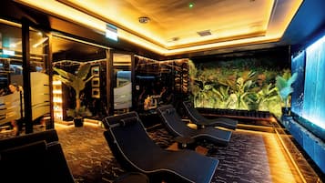A modern lounge area with seating and a large wall-mounted screen.