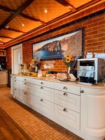 Una cocina con una isla grande, una cafetera y una pared decorativa con un paisaje de montaña.