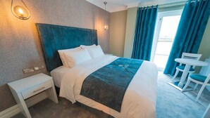 Una habitación de hotel con cama, mesita de noche y un escritorio pequeño con sillas.