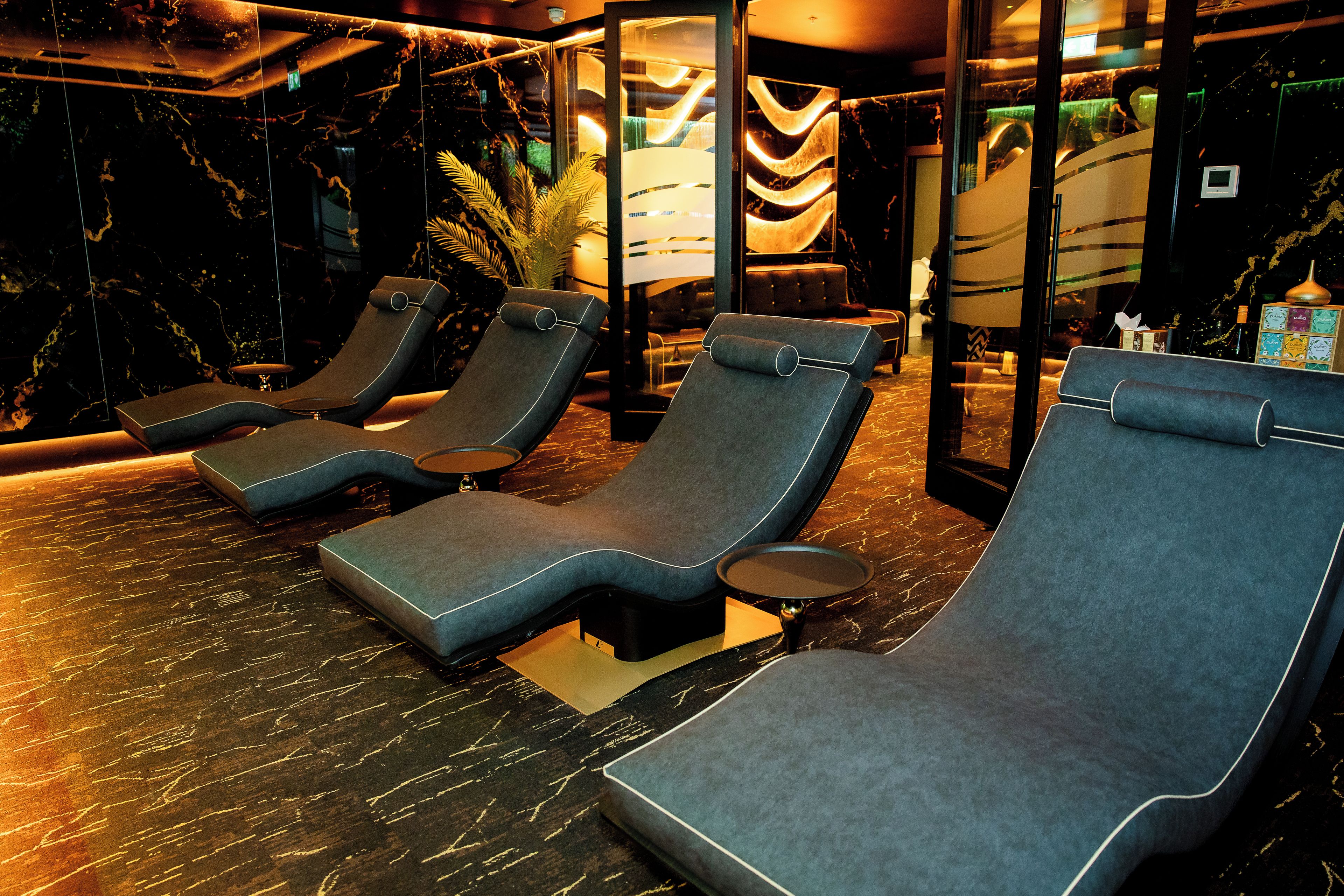 A spa area with reclining chairs, a marble floor, and a glass partition.