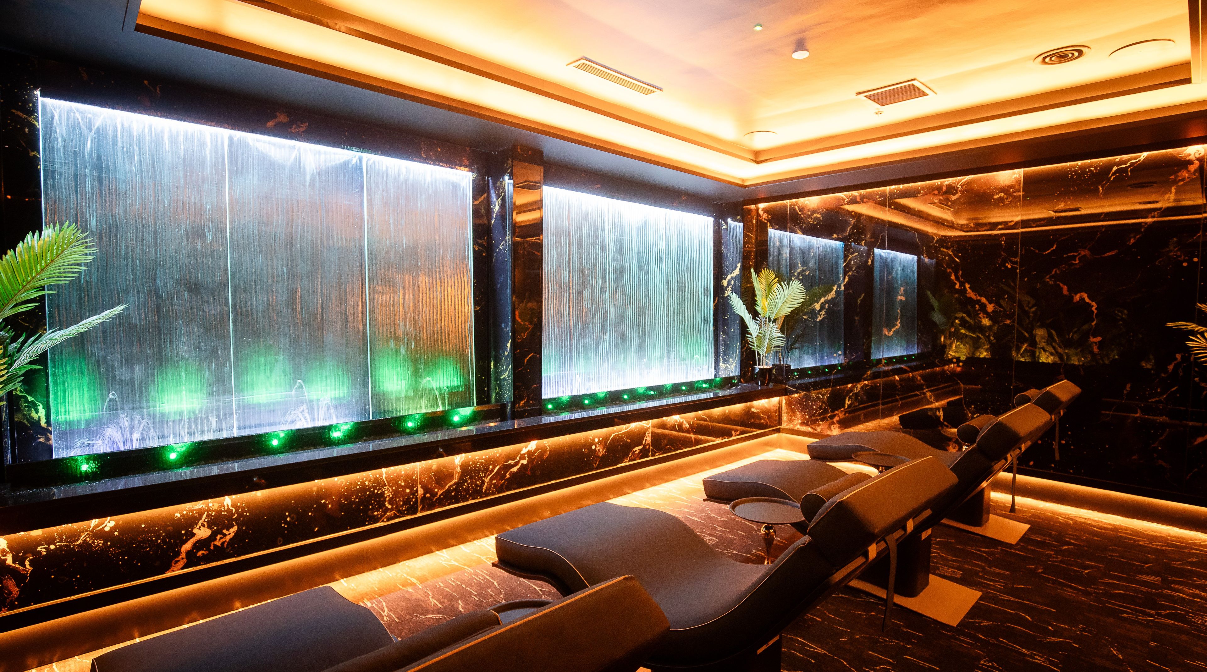 A modern lounge area with a waterfall feature, seating, and a marble floor.