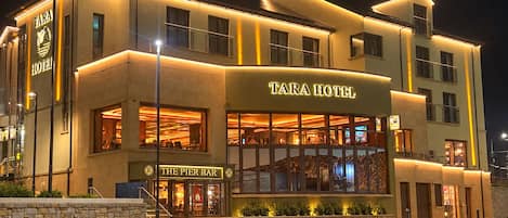 A multi-story hotel with a prominent sign reading 'TARA HOTEL' and a bar named 'THE PIER BAR' on the ground floor.