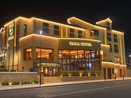 Un hotel de varios pisos con un letrero llamativo que dice 'TARA HOTEL' y un bar llamado 'THE PIER BAR' en la planta baja.