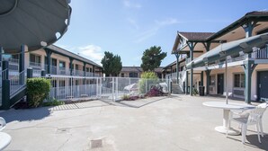 A courtyard with outdoor seating, a covered area, and a building with multiple balconies. - Best Whittier Inn (Whittier)
