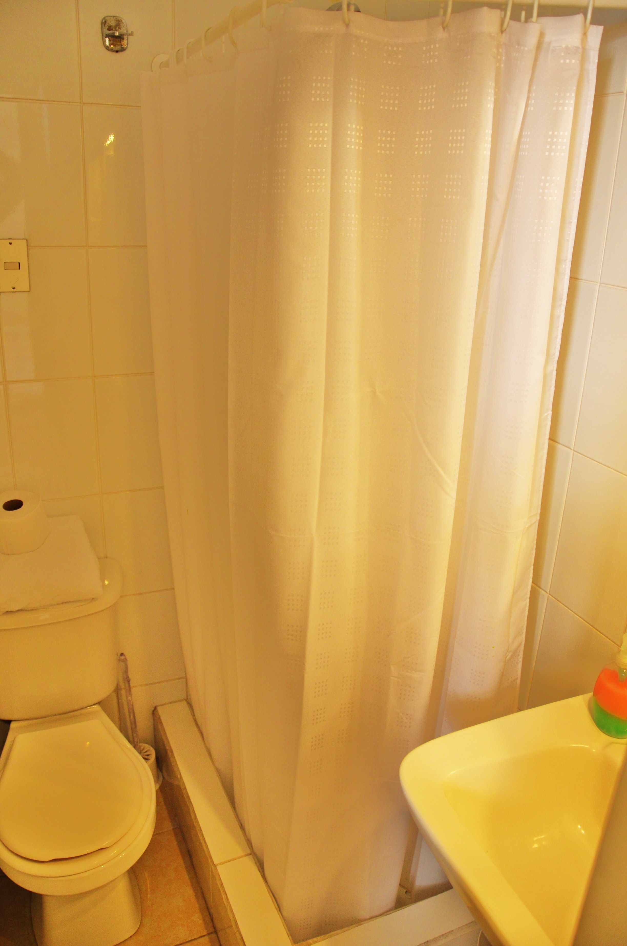 A bathroom with a toilet, a shower curtain, and a sink.