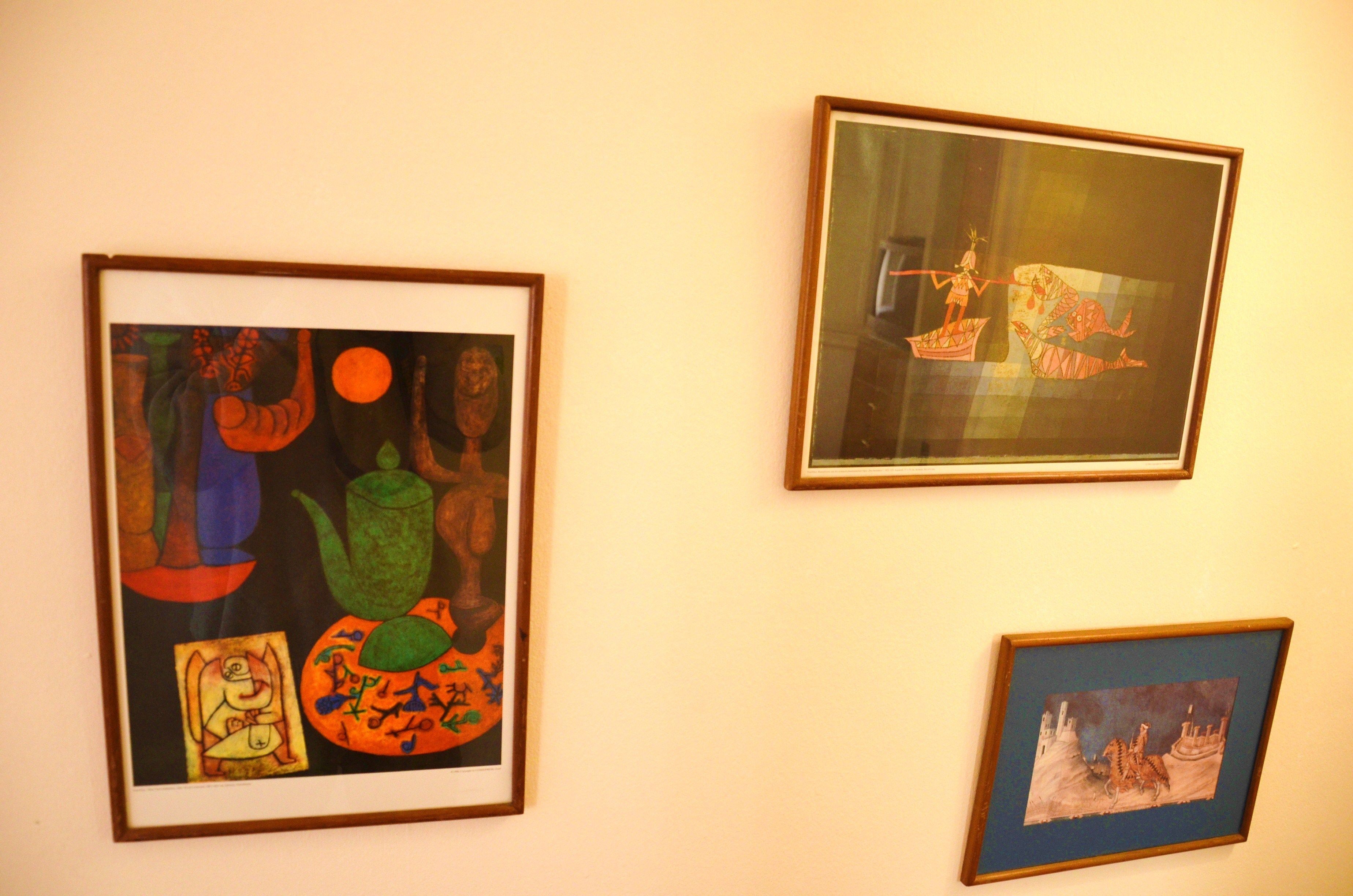 Drie kunstwerken in lijsten aan een muur.