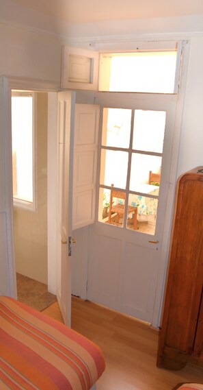 Una habitación con puerta de madera, una ventana y una cama con ropa de cama a rayas.