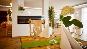 A dining table set with wine glasses, a candle, and a vase with a white flower. - Hotel Sonnenhof Dietzenbach (Dietzenbach)