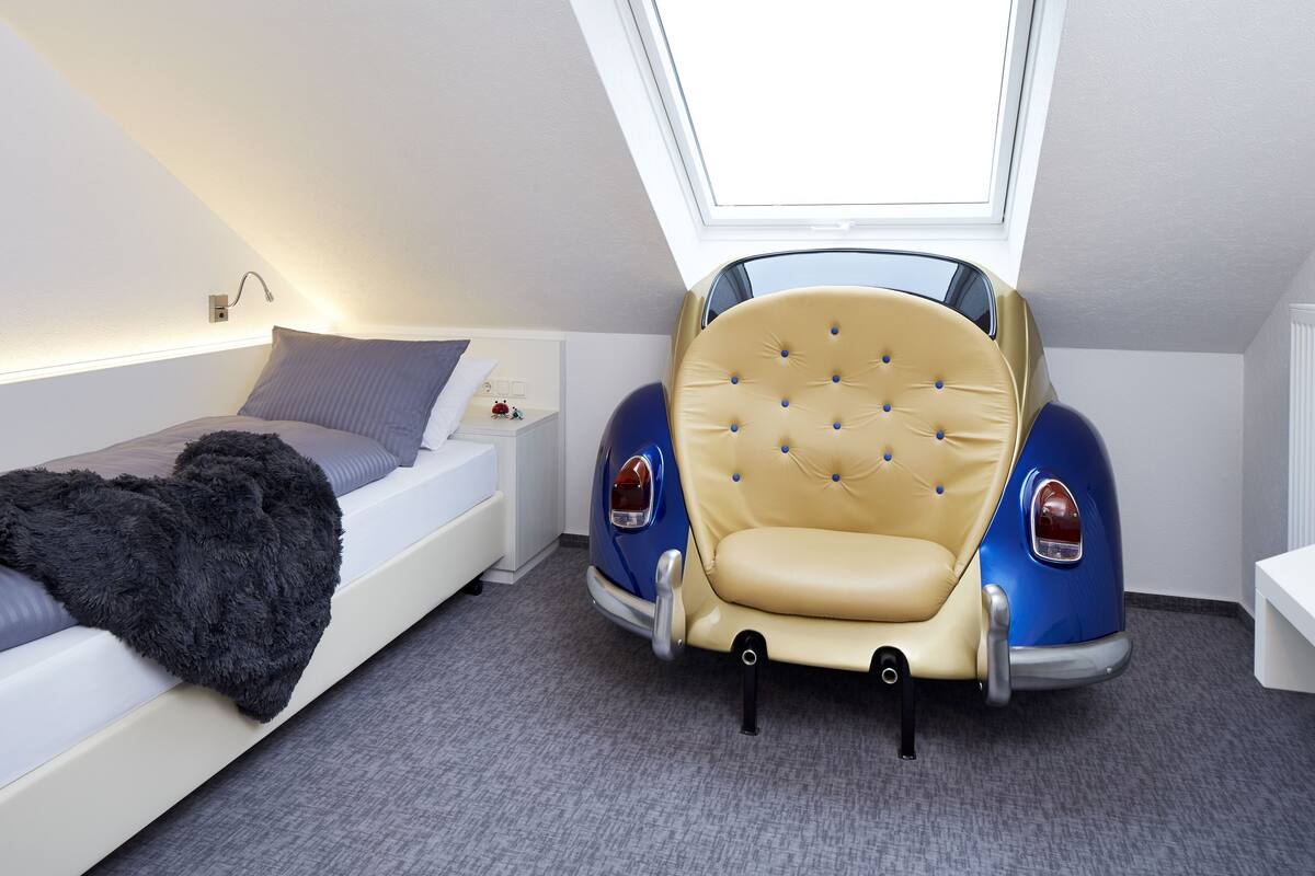 Une chambre avec un lit superposé, un fauteuil capitonné et une lucarne.
