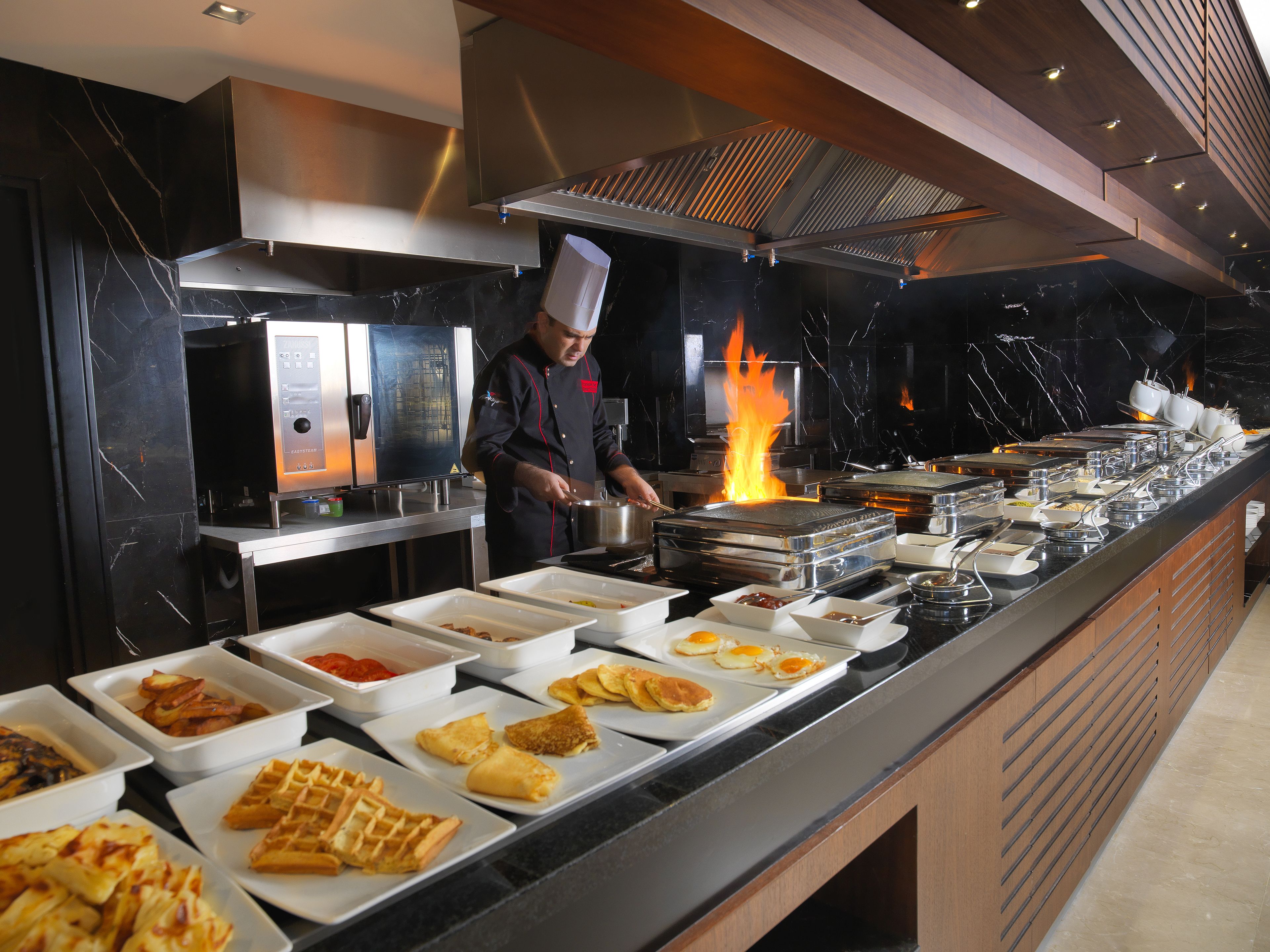 Un bufé con diferentes alimentos y un chef preparando comida.