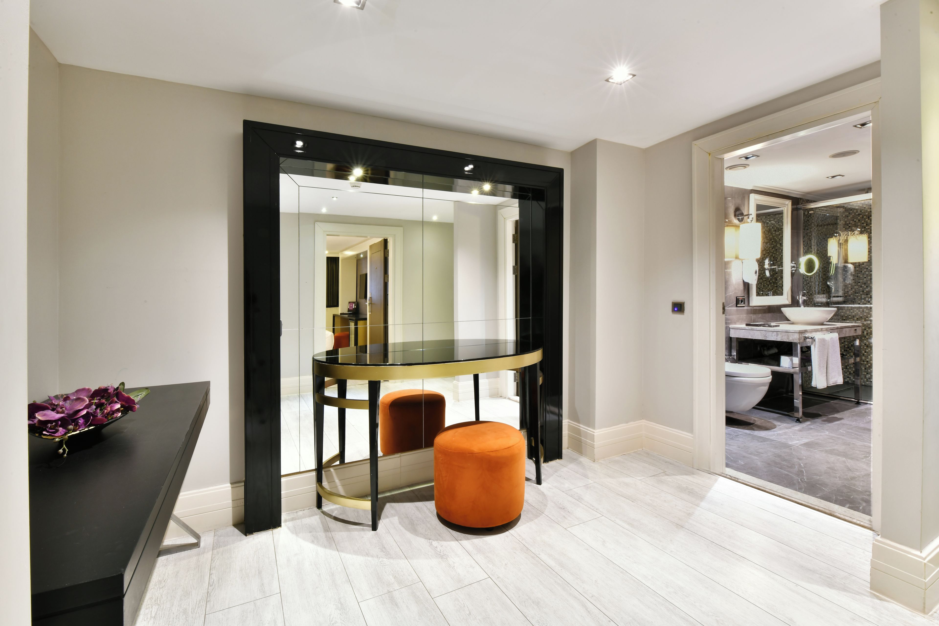 A modern bathroom with a glass-enclosed vanity, a toilet, and a sink.