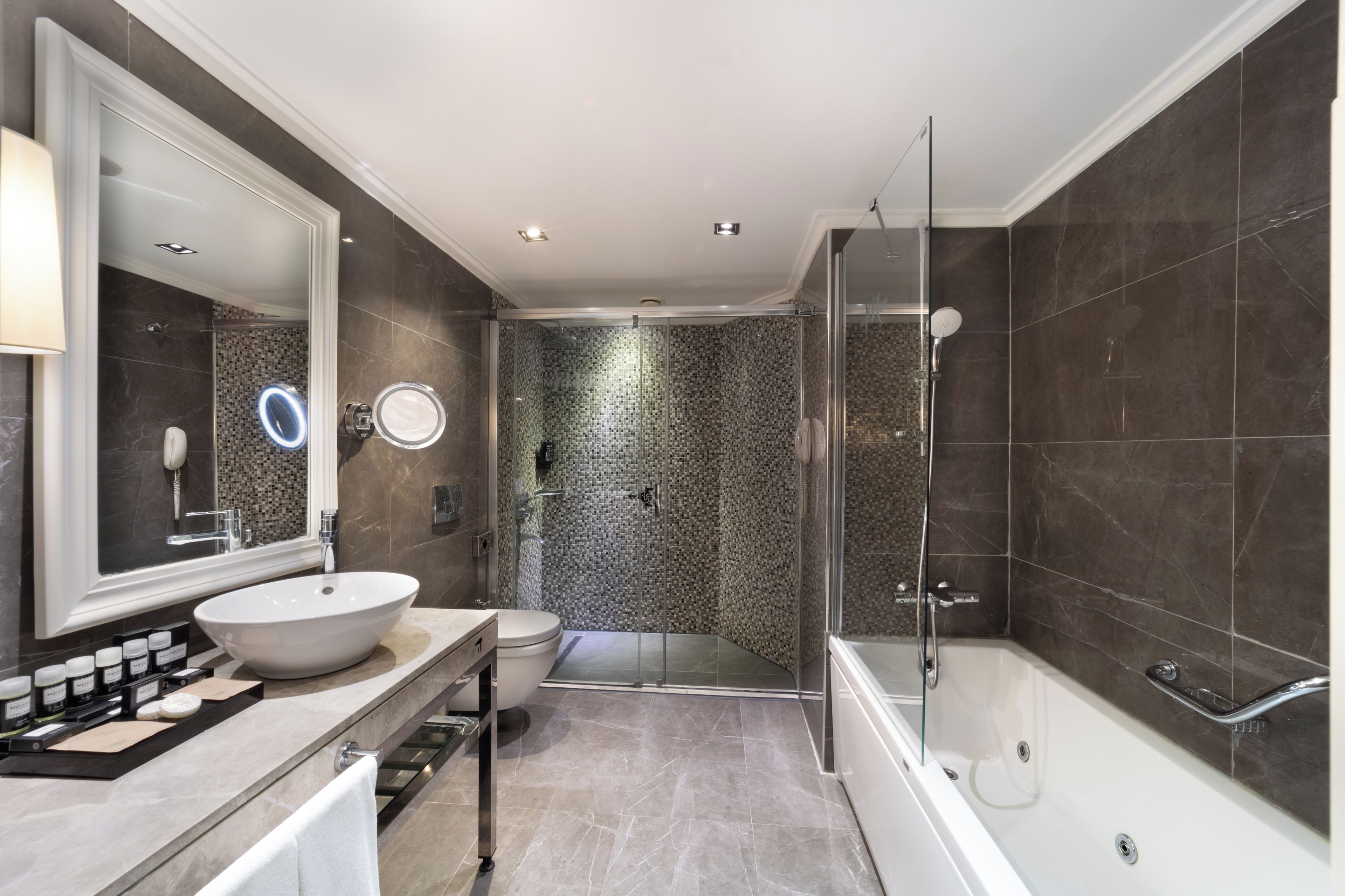 A modern bathroom with a large mirror, a sink, a toilet, and a shower area.