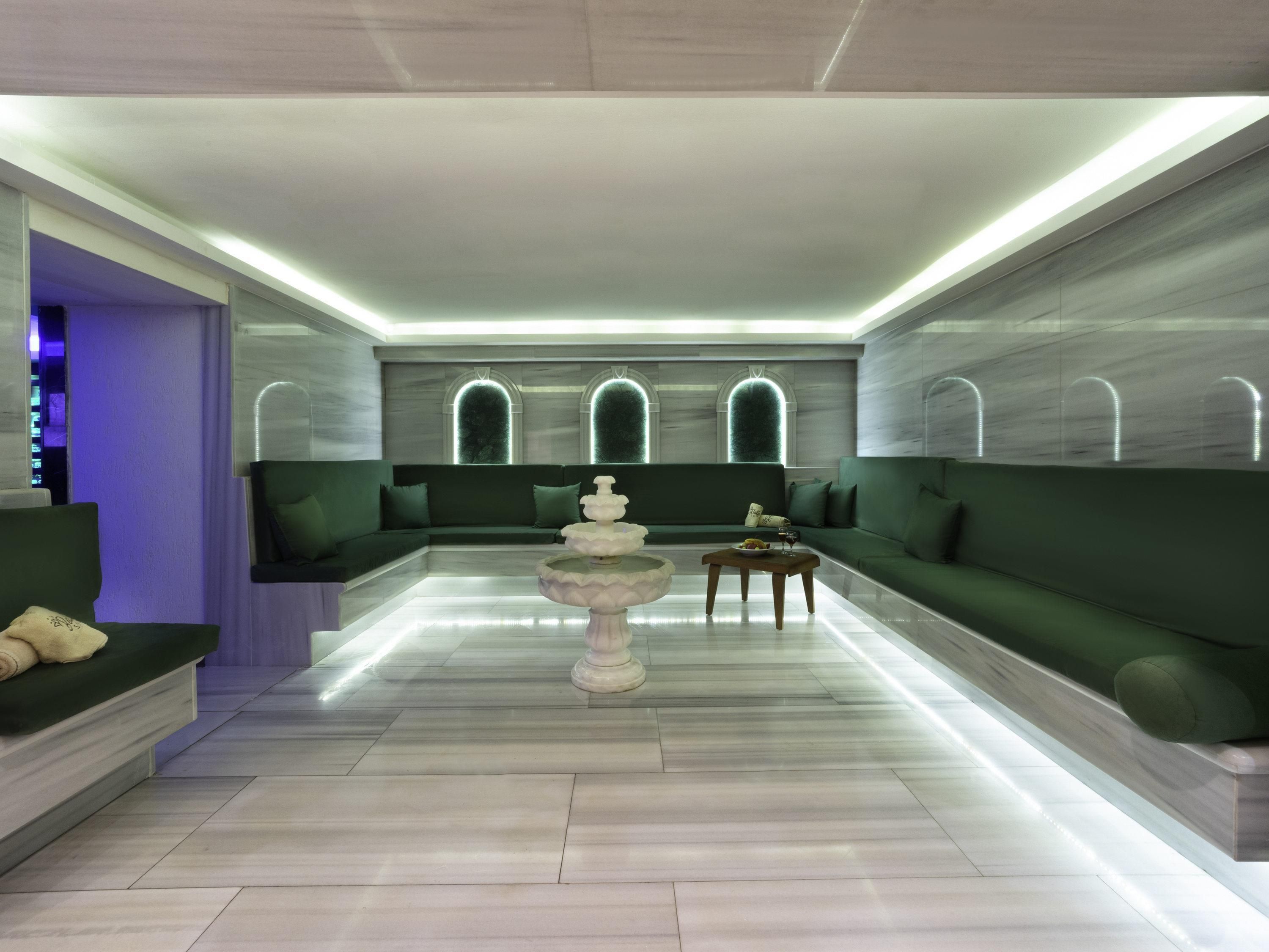 A modern interior with a central seating area, a decorative fountain, and a marble floor.