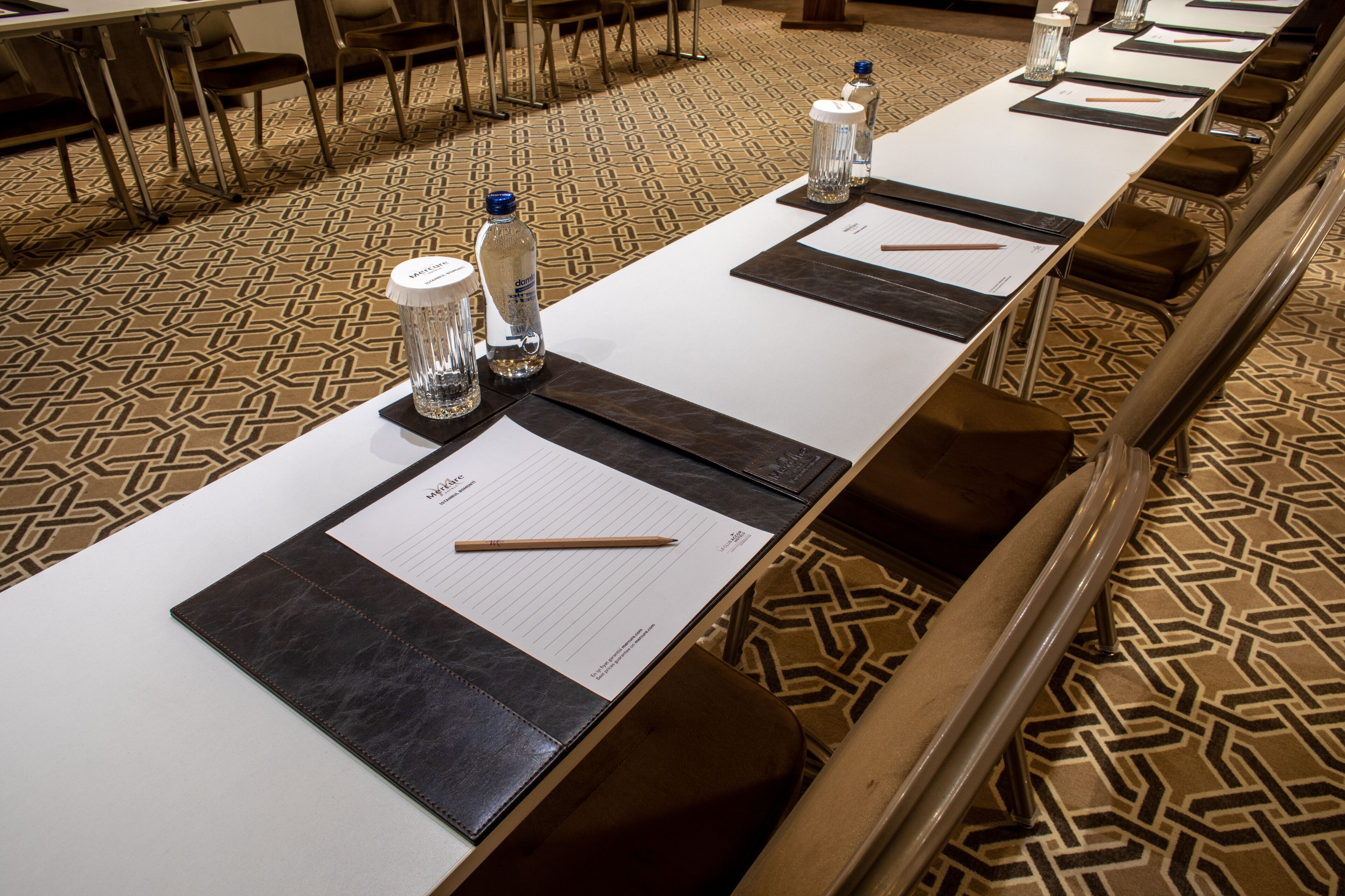 A conference room with a long table, chairs, water bottles, and notepads.