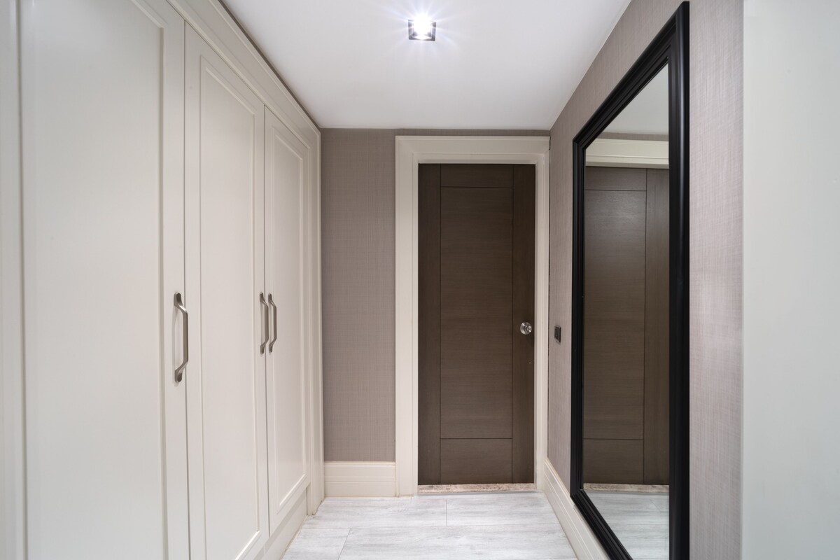 A hallway with a white door, a mirror, and a wardrobe.