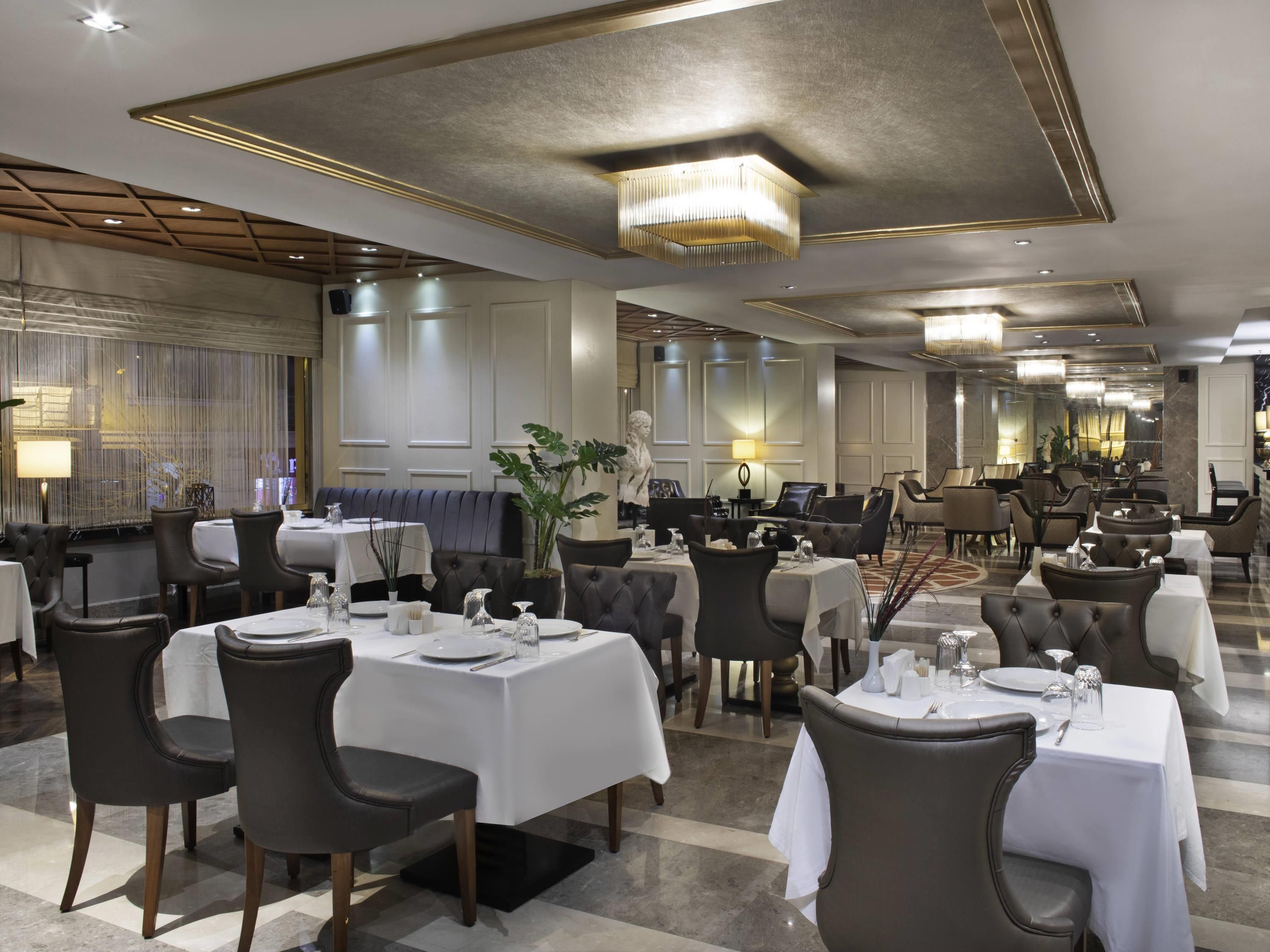 A spacious dining area with multiple tables, chairs, and a chandelier.