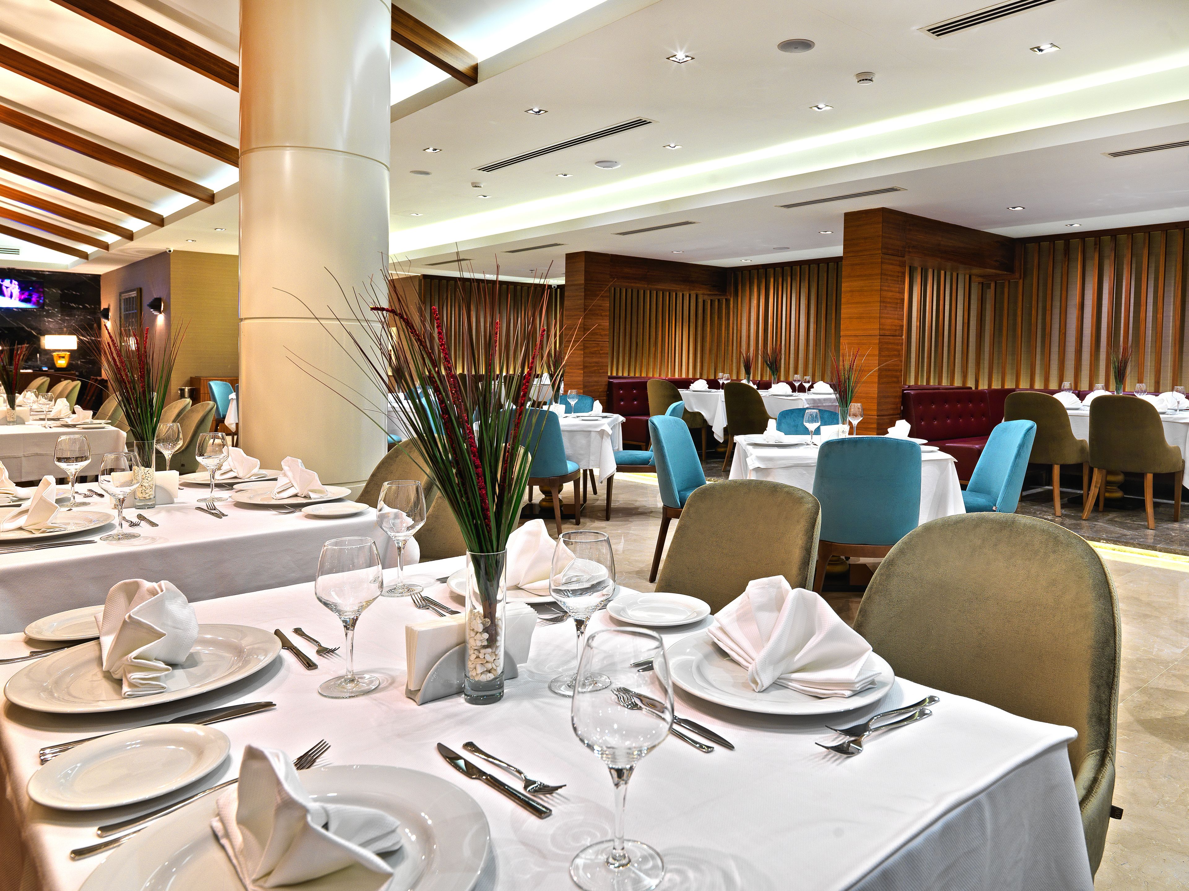 A restaurant with tables set for dining, featuring white tablecloths and neatly arranged silverware.