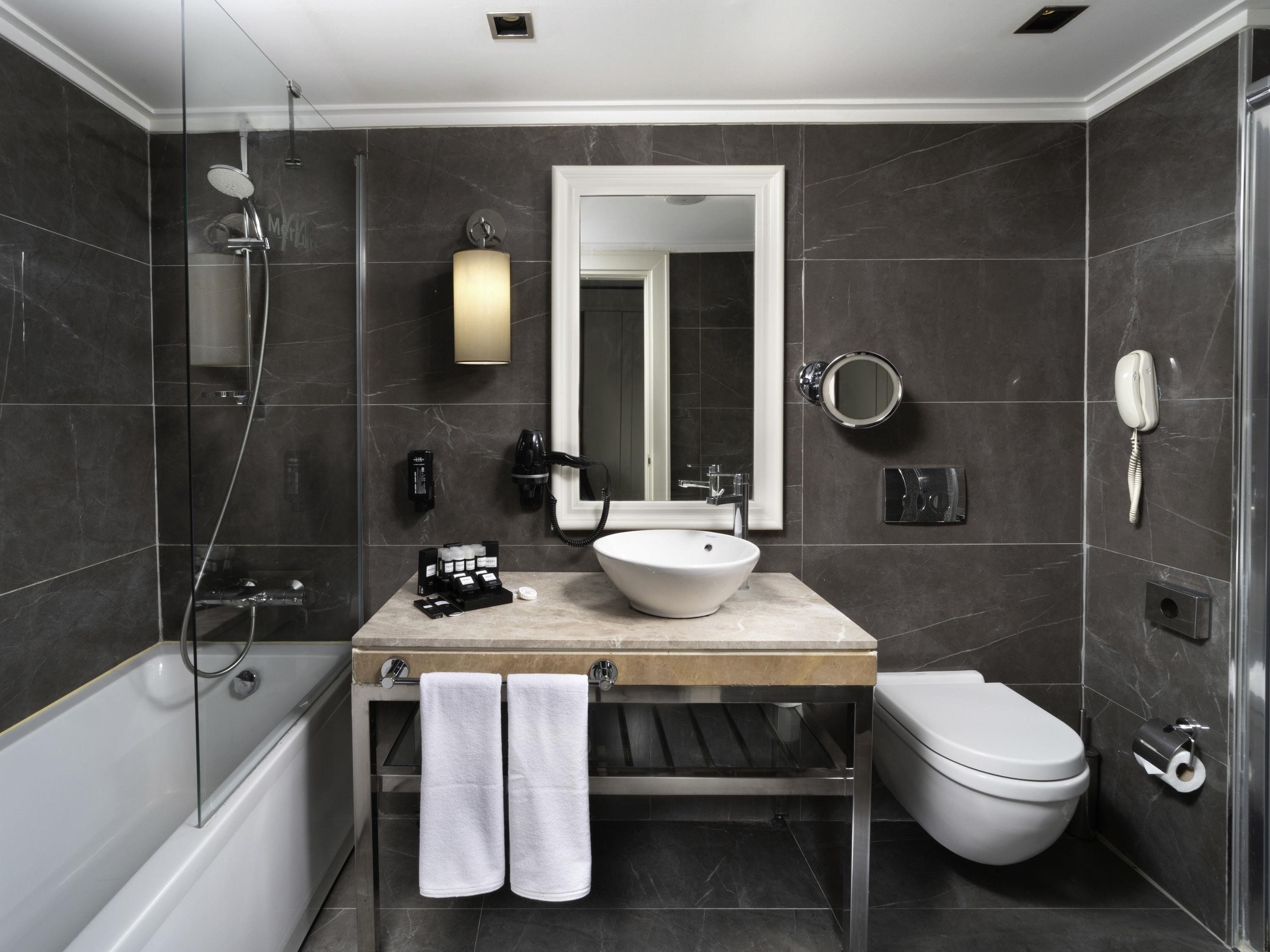 A modern bathroom with a glass-enclosed shower, a white sink, and a toilet.