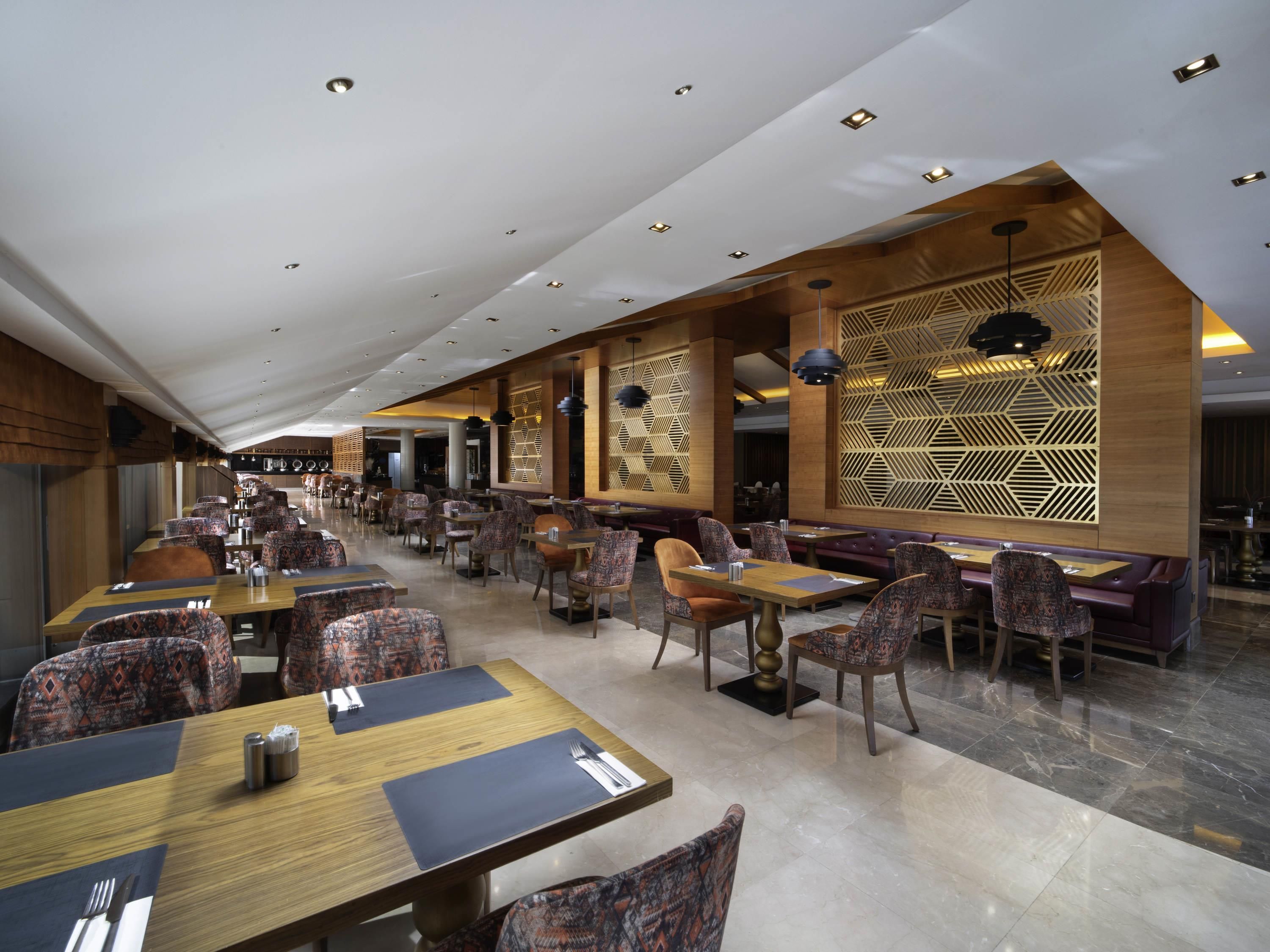 Een ruime eetzaal met hoge plafonds, verschillende zithoeken en een modern interieur.
