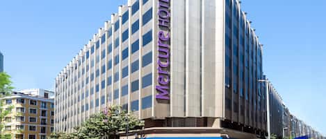Ett modernt hotell med en framträdande, vertikal skylt där det står ”Mercure Hotel”.