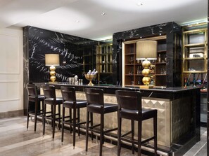 Eine Bar mit Marmorwänden, einer Theke und mehreren Barhocker.