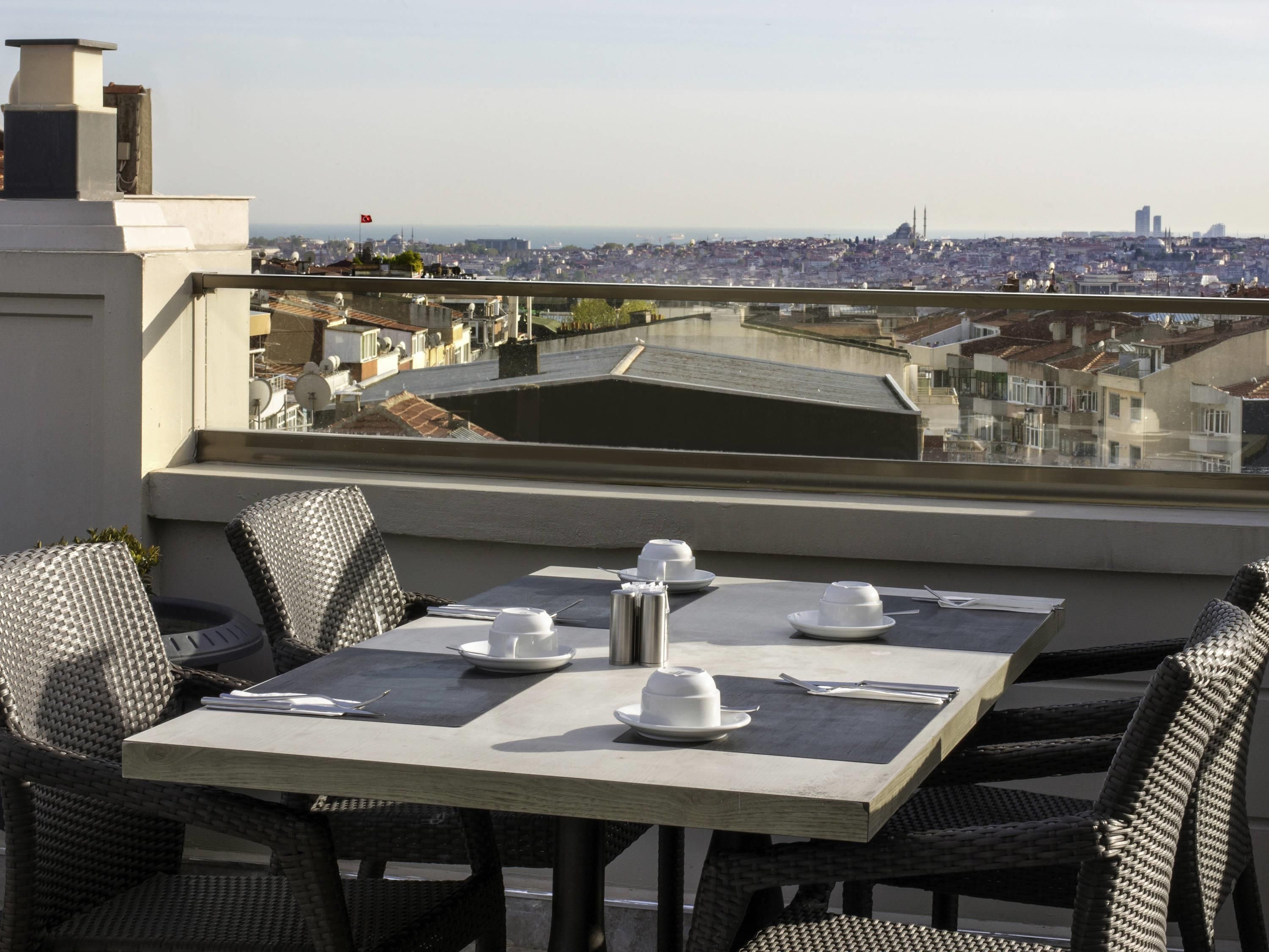 A dining area with a table set for four, overlooking a cityscape.