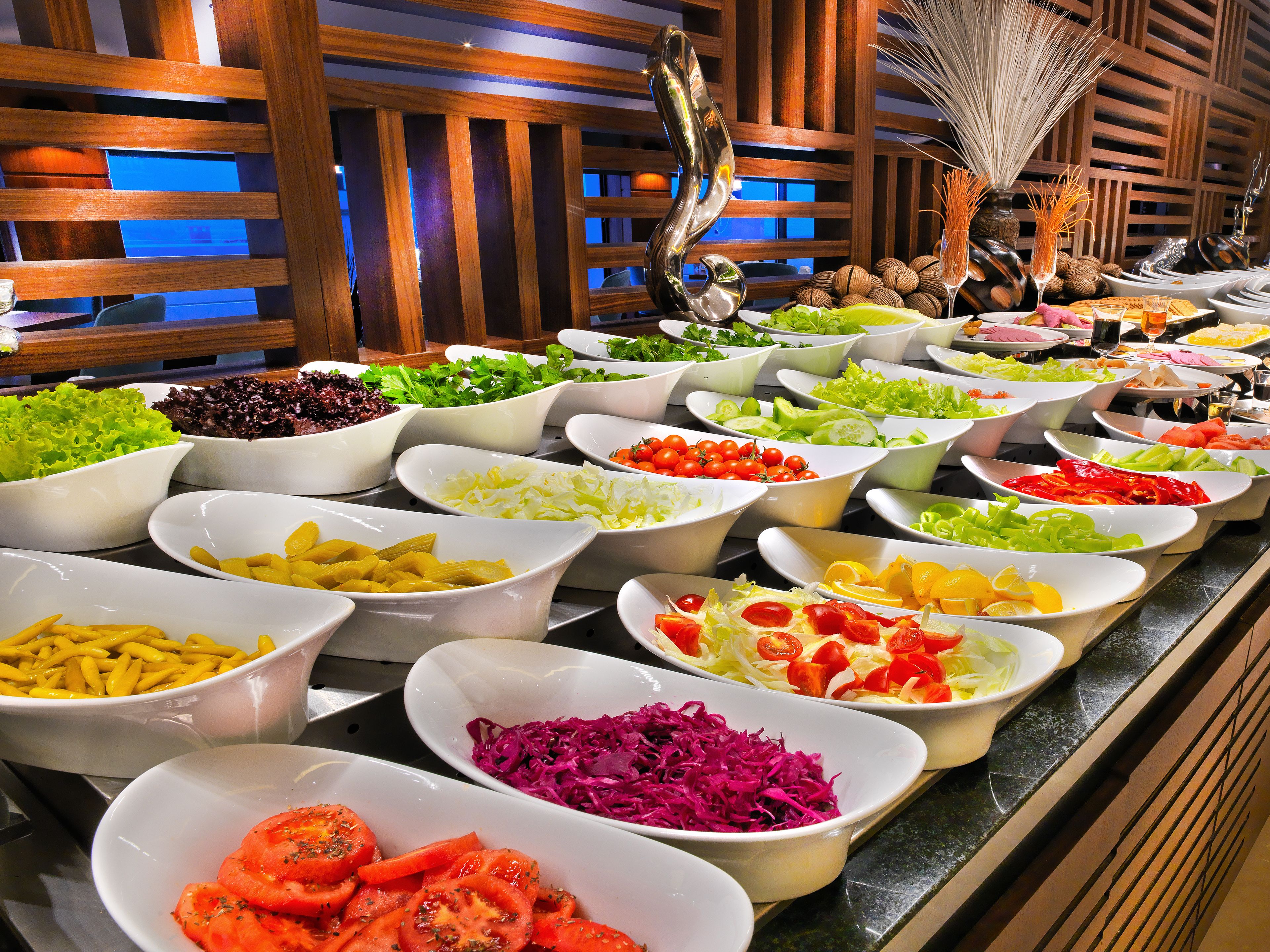 A buffet with various dishes including salads, fruits, and vegetables.