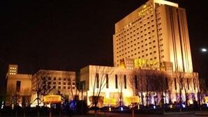 A multi-story hotel with a modern design, featuring a prominent entrance and a well-lit facade.