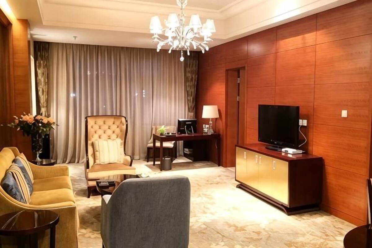 Una sala de estar con sofá, sillón, televisor y un mueble de madera.