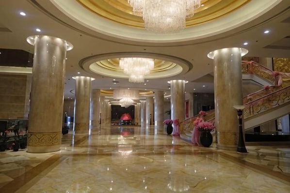 A spacious lobby with high ceilings, large chandeliers, and a grand staircase. - Guo Erluosi Hotel (Songyan)