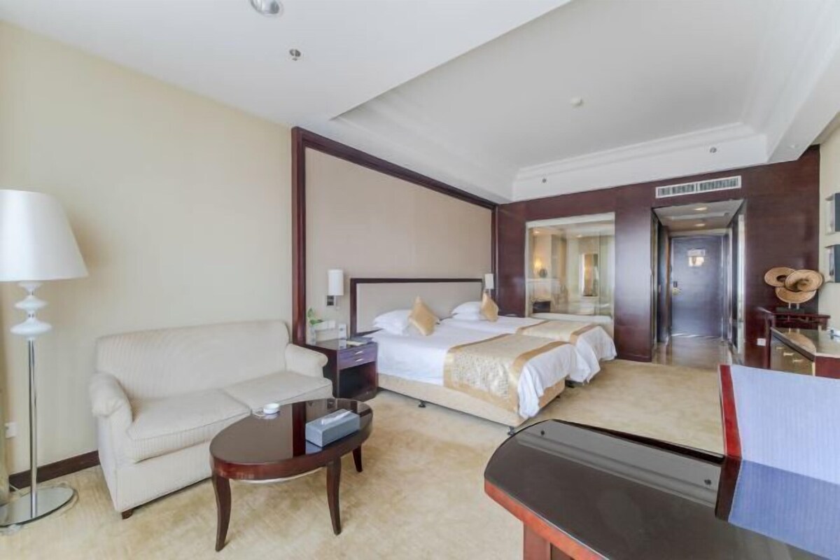 Una habitación de hotel con cama, sofá, escritorio y lámpara.